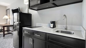 Una cocina moderna con microondas integrado, cafetera y pileta de acero inoxidable.