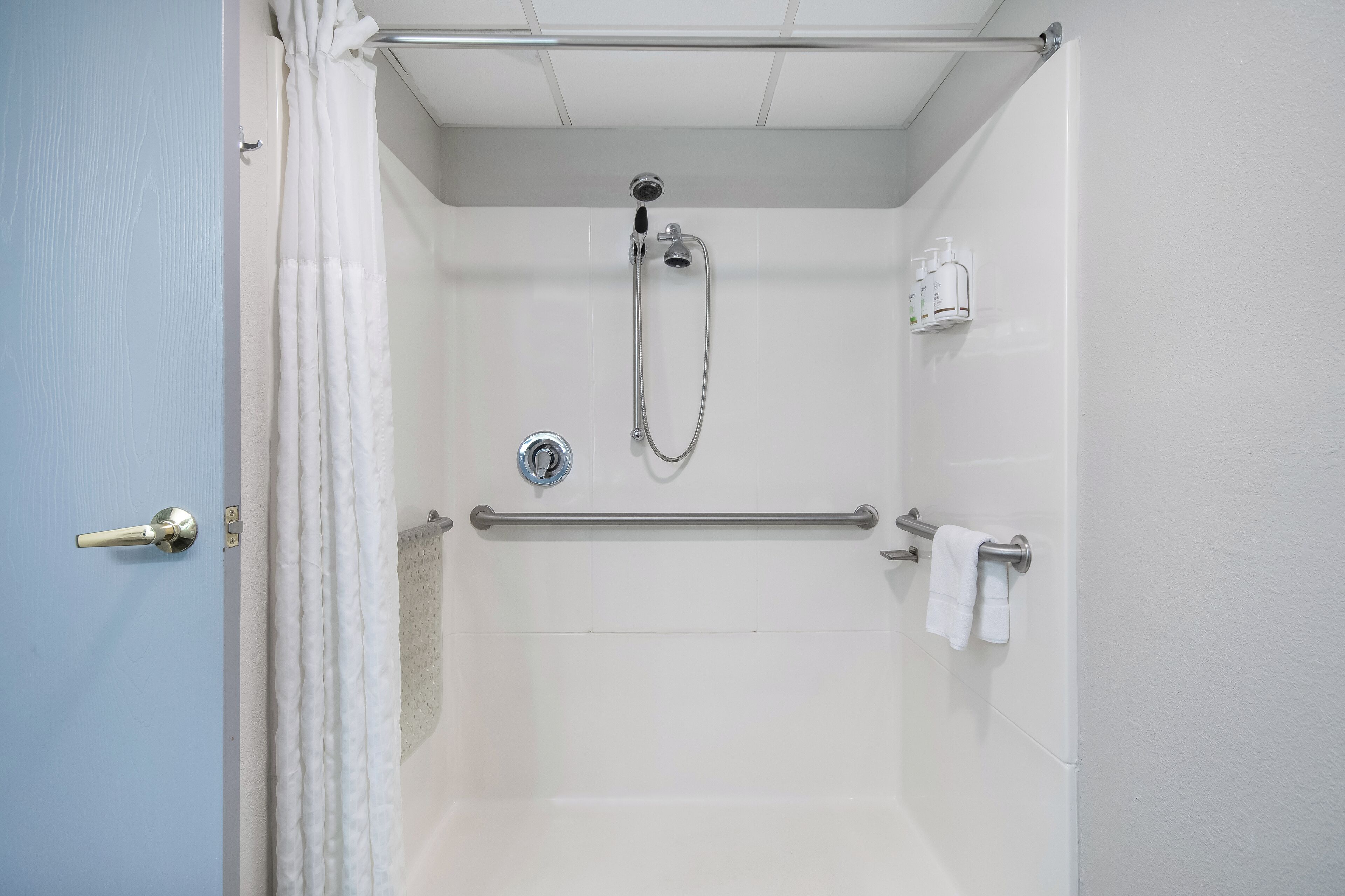 Un espace douche équipé d’une barre d’appui, d’un porte-serviettes et d’un pommeau de douche.