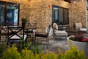 An outdoor patio with stone walls, tables, chairs, and potted plants.