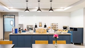 A modern kitchen area with a central island, barista station, and seating area.