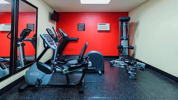 A gym with cardio machines, weightlifting equipment, and a mirrored wall.