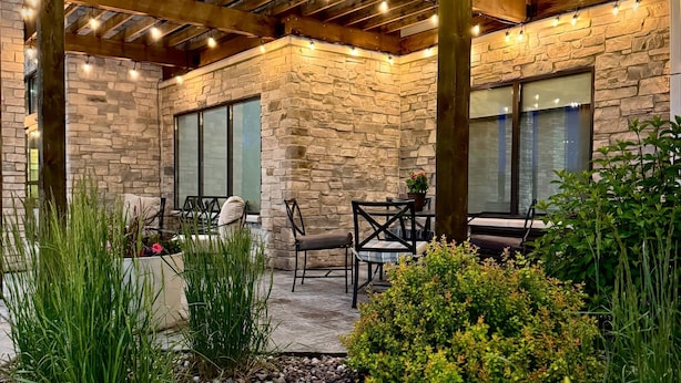 An outdoor patio with stone walls, wooden beams, and string lights.