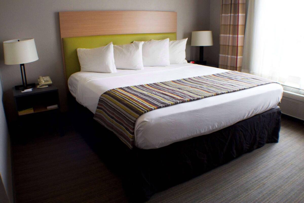 A hotel room with a large bed, two bedside tables, and a window with curtains.
