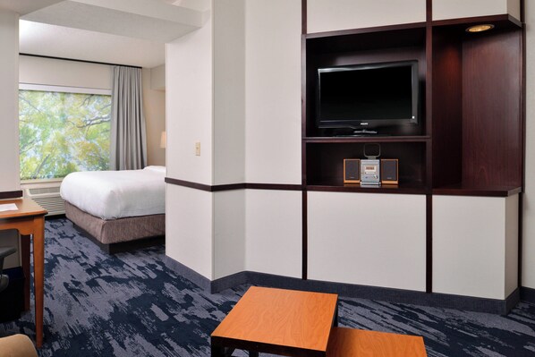 A hotel room with a bed, a desk, a television, and a window with a view of trees. - Fairfield Inn & Suites by Marriott Beloit (Beloit)