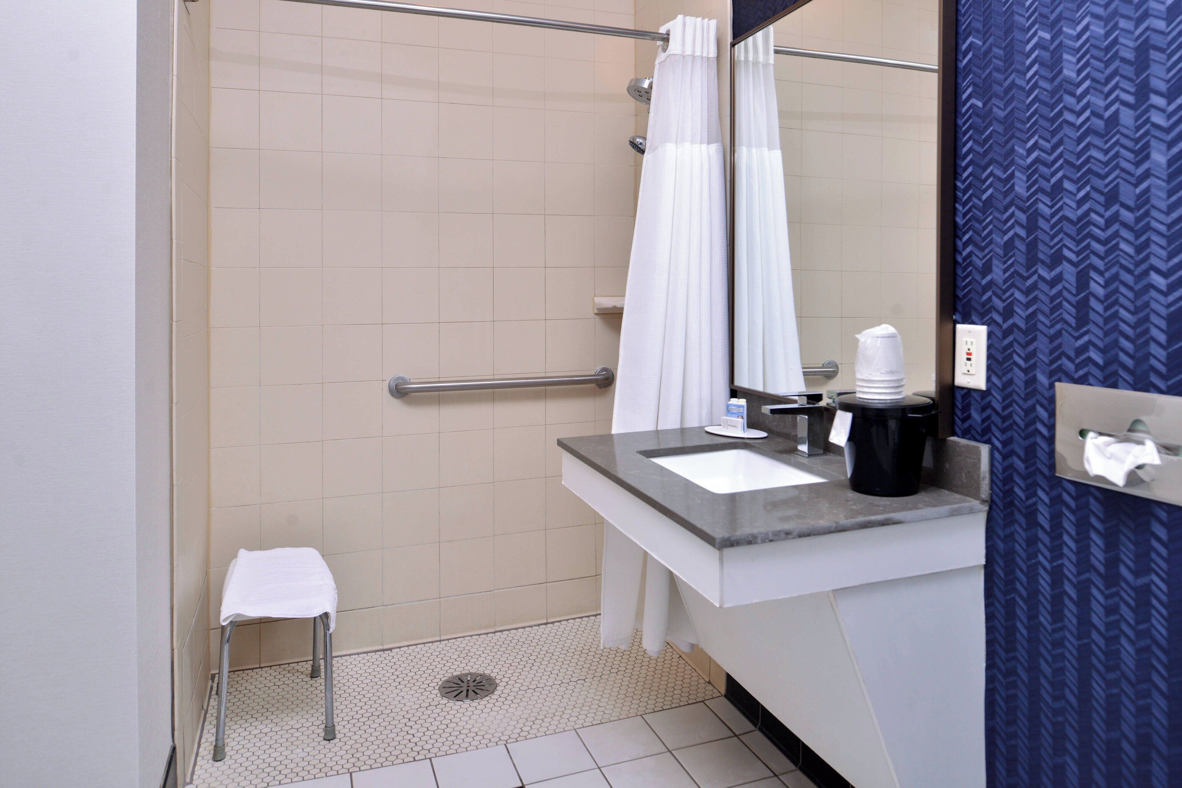 Une salle de bain équipée d’une douche, d’un lavabo, d’un porte-serviettes et d’un miroir.