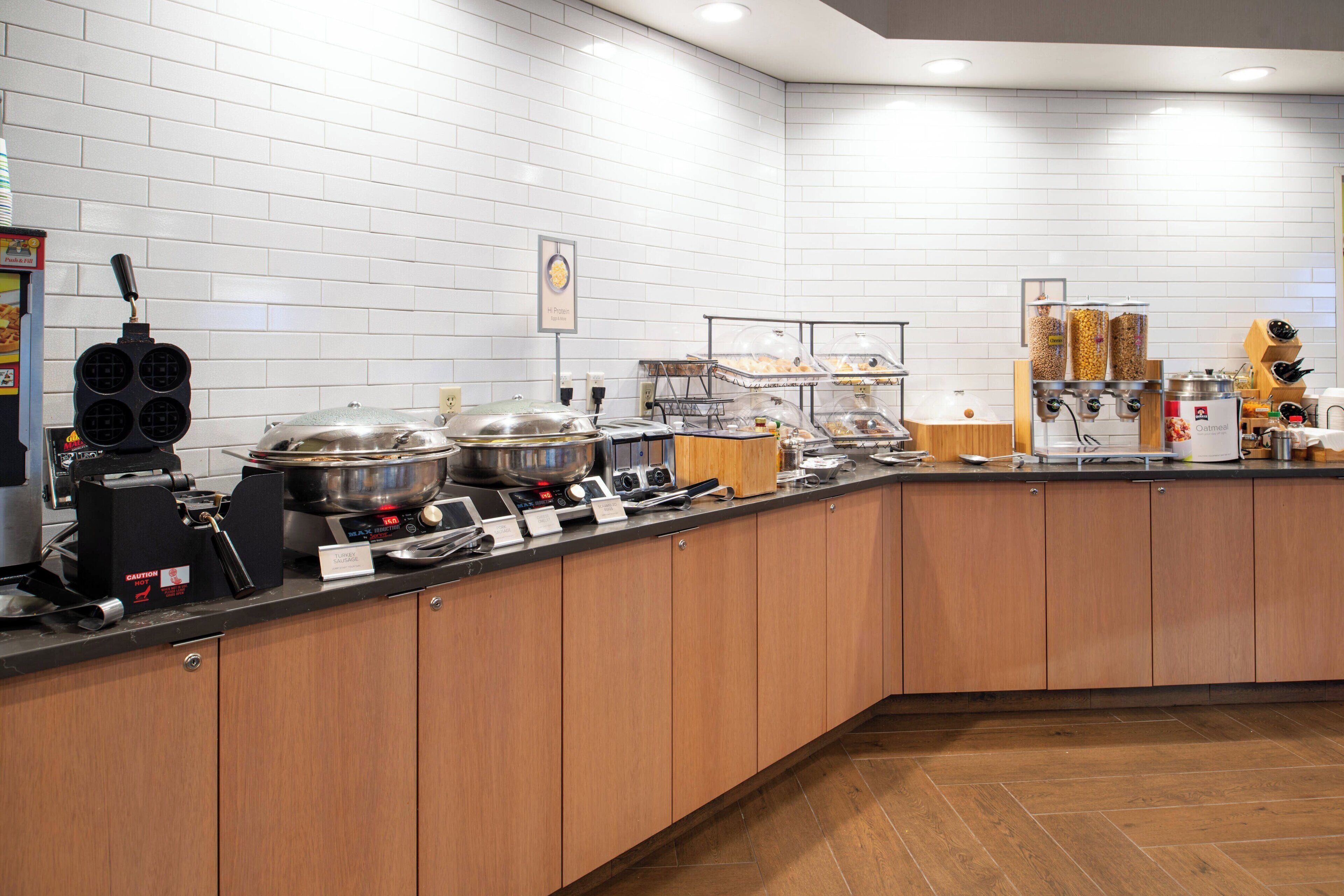 Une cuisine équipée d’un buffet, comprenant un appareil à gaufres, une cuisinière et divers récipients pour aliments.