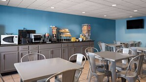 A restaurant with a blue wall, white ceiling, and metal chairs and tables. - Days Inn by Wyndham Neenah (Neenah)