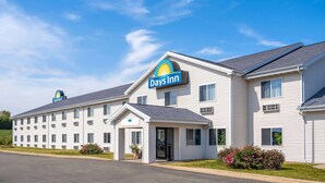A Days Inn hotel with a simple, single-story structure, a central entrance, and a clear blue sky. - Days Inn by Wyndham Neenah (Neenah)