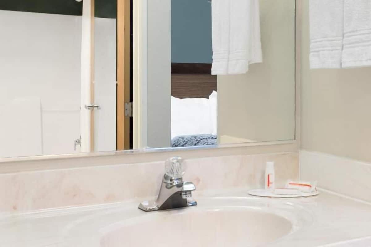 Un baño con lavabo, espejo y perchero para toallas.