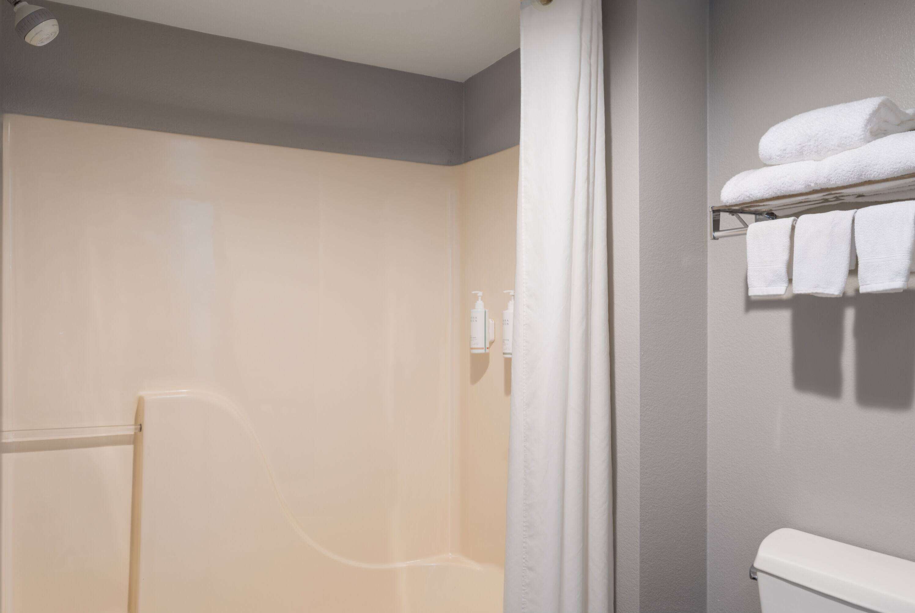 A bathroom with a shower, a towel rack with towels, and a toilet.