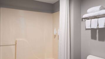 A bathroom with a shower, a towel rack with towels, and a toilet.