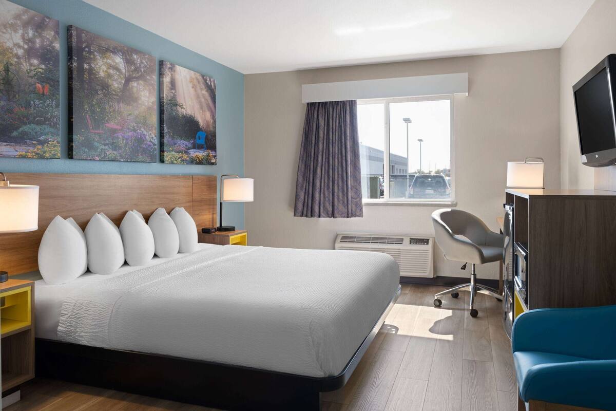 Habitación de hotel con una cama grande, un escritorio con ordenador, una silla y un televisor.