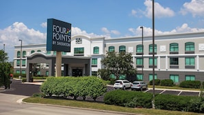 Un hotel Four Points by Sheraton con fachada moderna, estacionamiento y jardines bien cuidados.