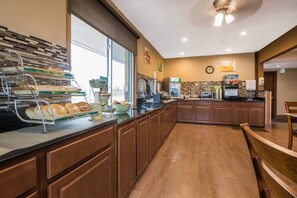 A modern kitchen with a buffet setup, a coffee machine, and a clock on the wall.