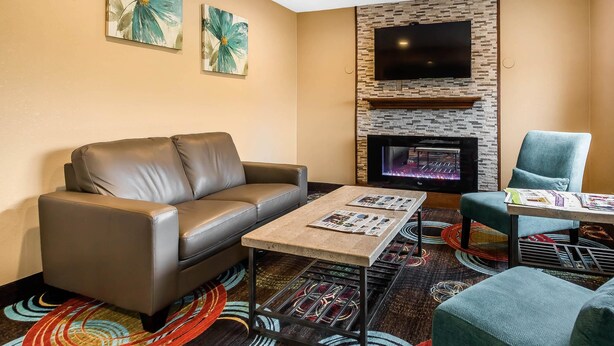 A modern living room with a leather sofa, a coffee table, and a TV mounted on a brick wall.