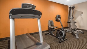 A gym with a treadmill, stationary bike, and weight machine.