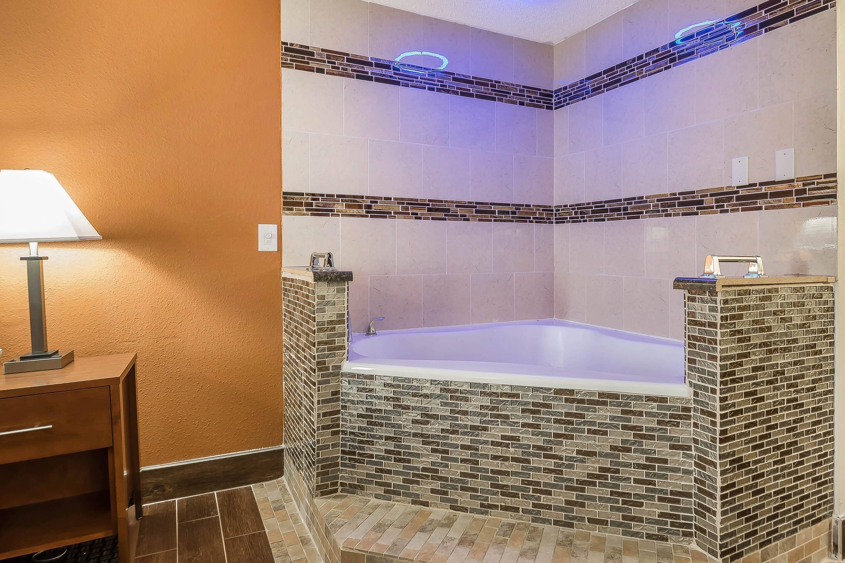 A bathroom with a bathtub, a towel rack, and a lamp on a side table.