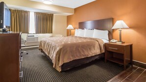 A hotel room with a bed, bedside lamps, a desk with a telephone, and a television.