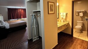Ein Hotelzimmer mit Bett, einem Badezimmer mit Toilette und Waschbecken sowie einem Flur mit Kleiderhaken.