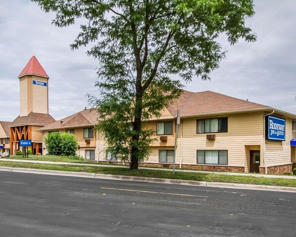 A motel with a red-roofed tower, a sign for 'Rodeway Inn & Suites', and a large tree in front.
