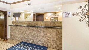 Ein Hotel-Rezeptionsbereich mit Steinwand, einer Uhr und einem Schild, das die Frühstückszeiten des Continental Breakfast angibt.