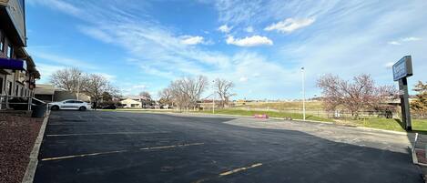 A parking lot with a building on the left, a sign for 'RODEWAY HOTEL & SQUATS' on the right, and a clear sky above.