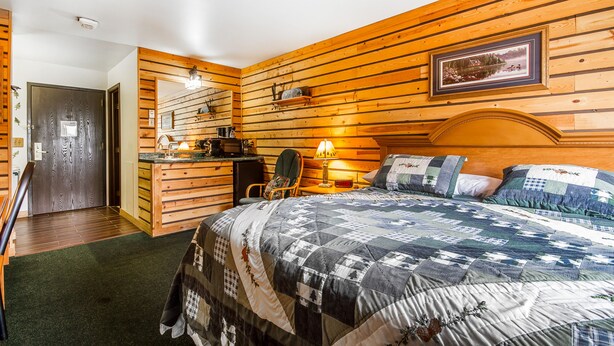 Ein Schlafzimmer mit Holzwänden, einem Bett, einem Schreibtisch und einem Stuhl.