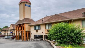 Ein Motel mit einem markanten Turm, einem überdachten Eingangsbereich und einem Parkplatz.