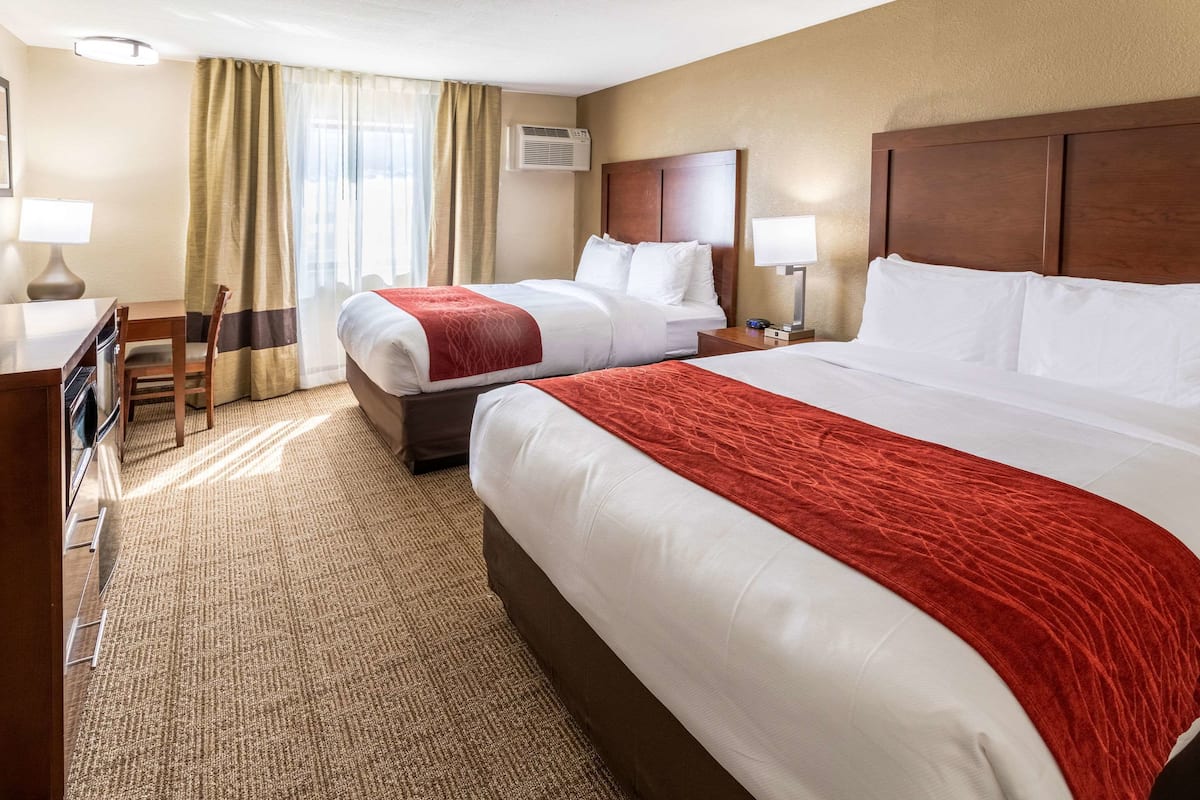 Une chambre d’hôtel avec deux lits, un bureau et une chaise.