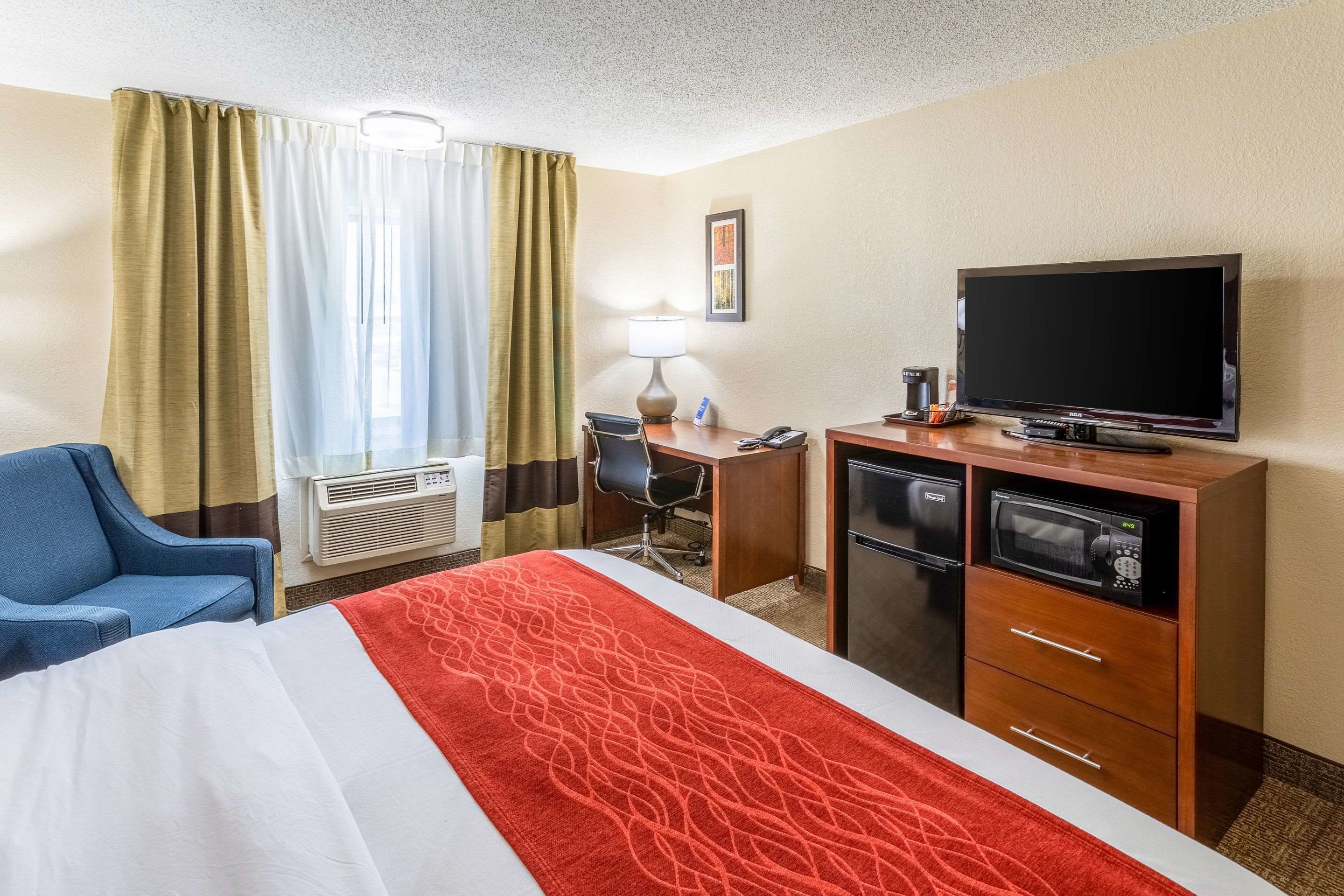 A hotel room with a bed, a desk, a television, a microwave, and a coffee maker.