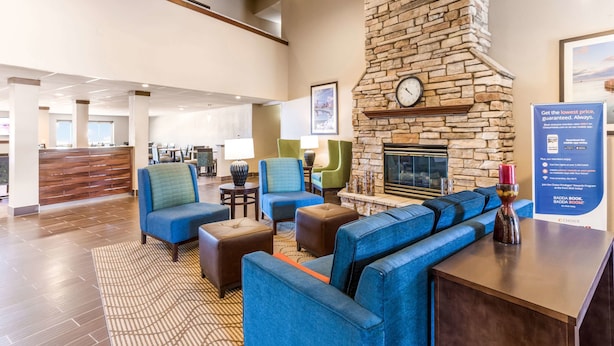 A lobby with a stone fireplace, blue seating, a reception desk, and a view of the dining area.