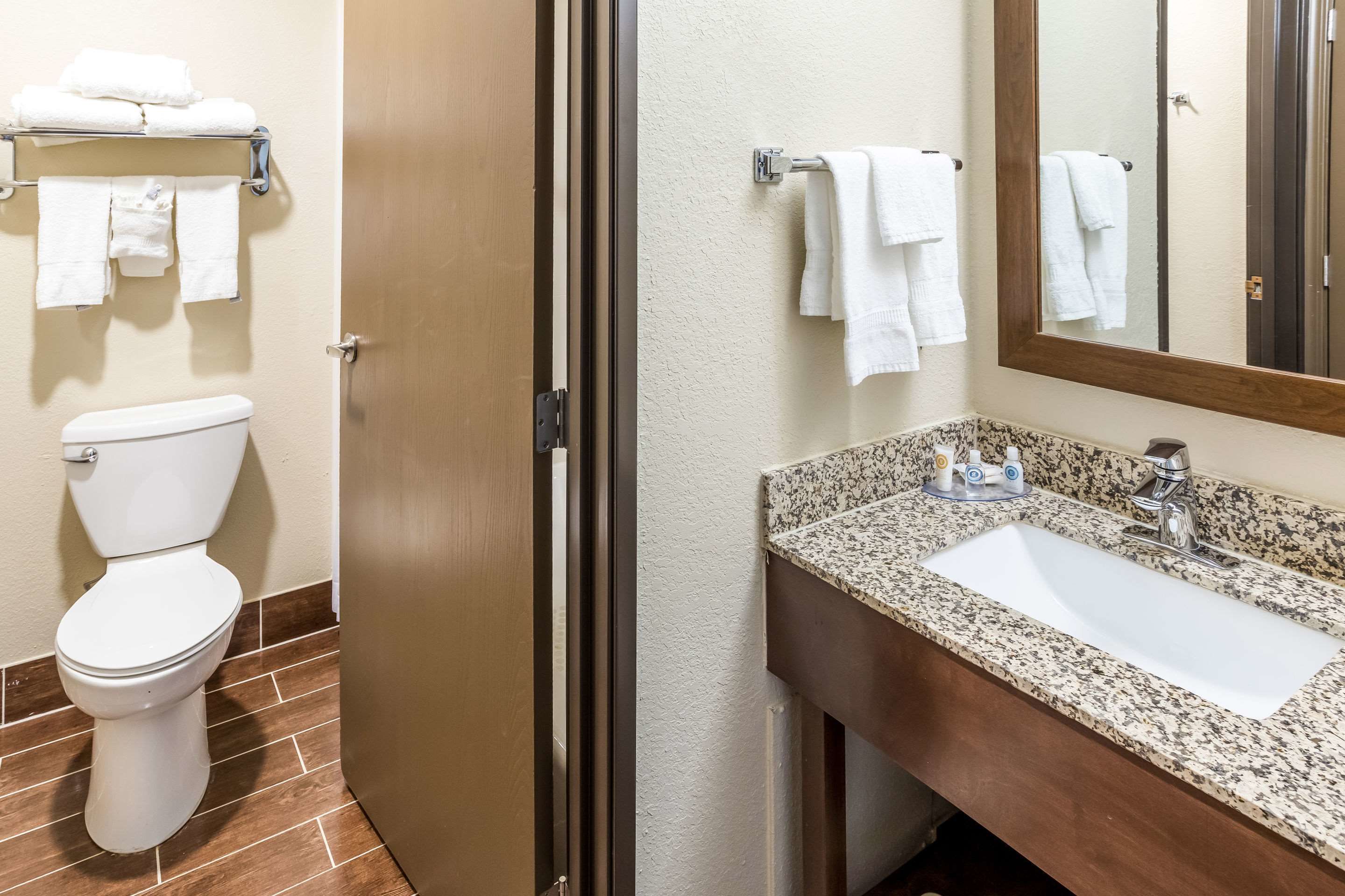 A bathroom with a toilet, a sink, a mirror, and a towel rack with towels.
