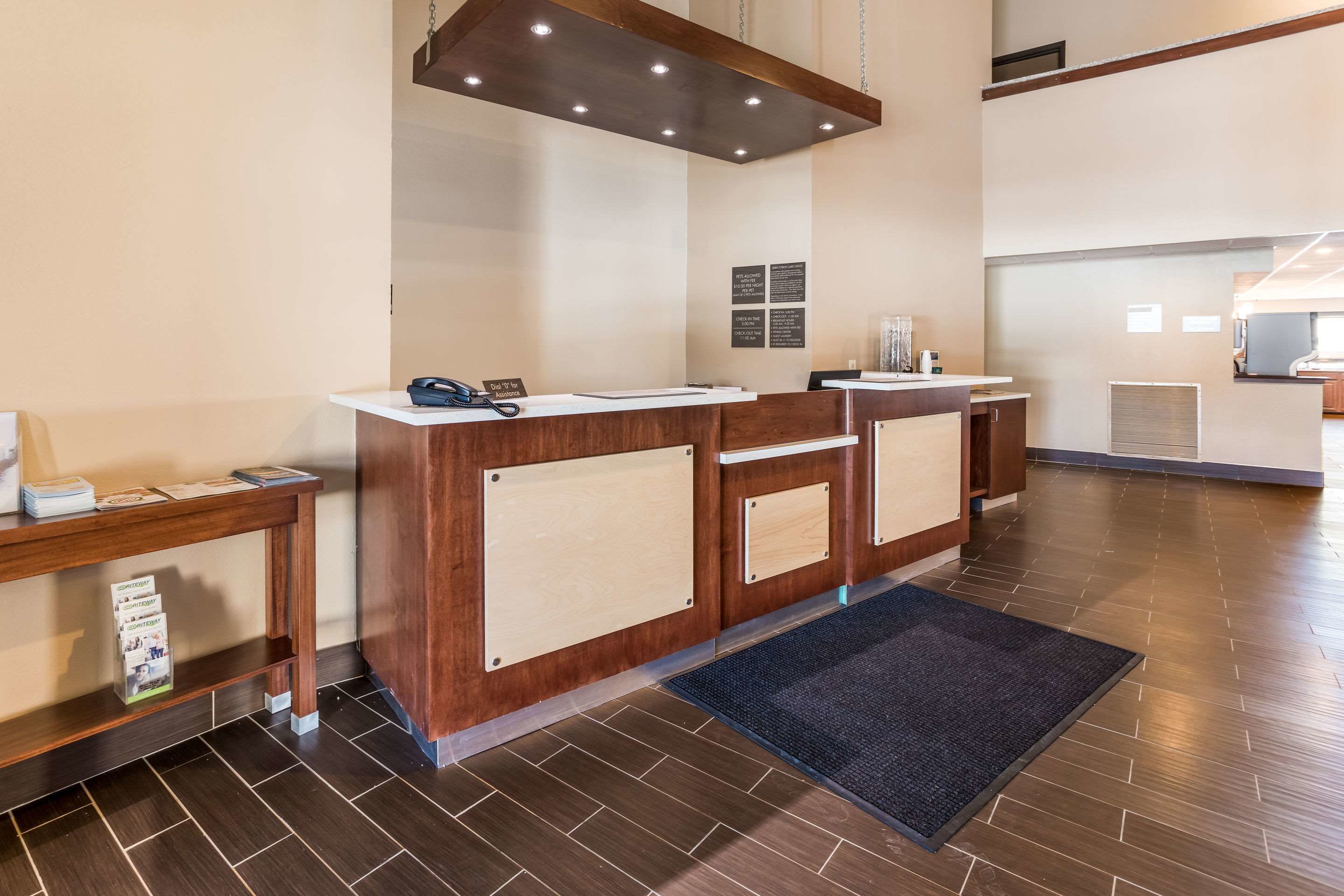 A reception area with a wooden reception desk, a phone, and informational posters on the wall.
