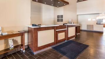 A reception area with a wooden reception desk, a phone, and informational posters on the wall.