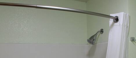 A bathroom with a shower area, a white bathtub, and a shower curtain.