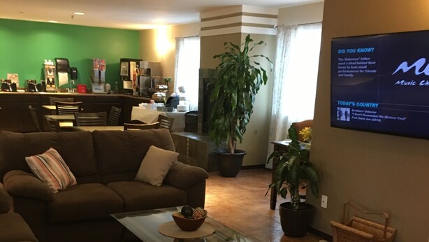 A living room with a sofa, coffee table, and a flat-screen TV mounted on the wall. - Cheyenne Guest Inn (Cheyenne)