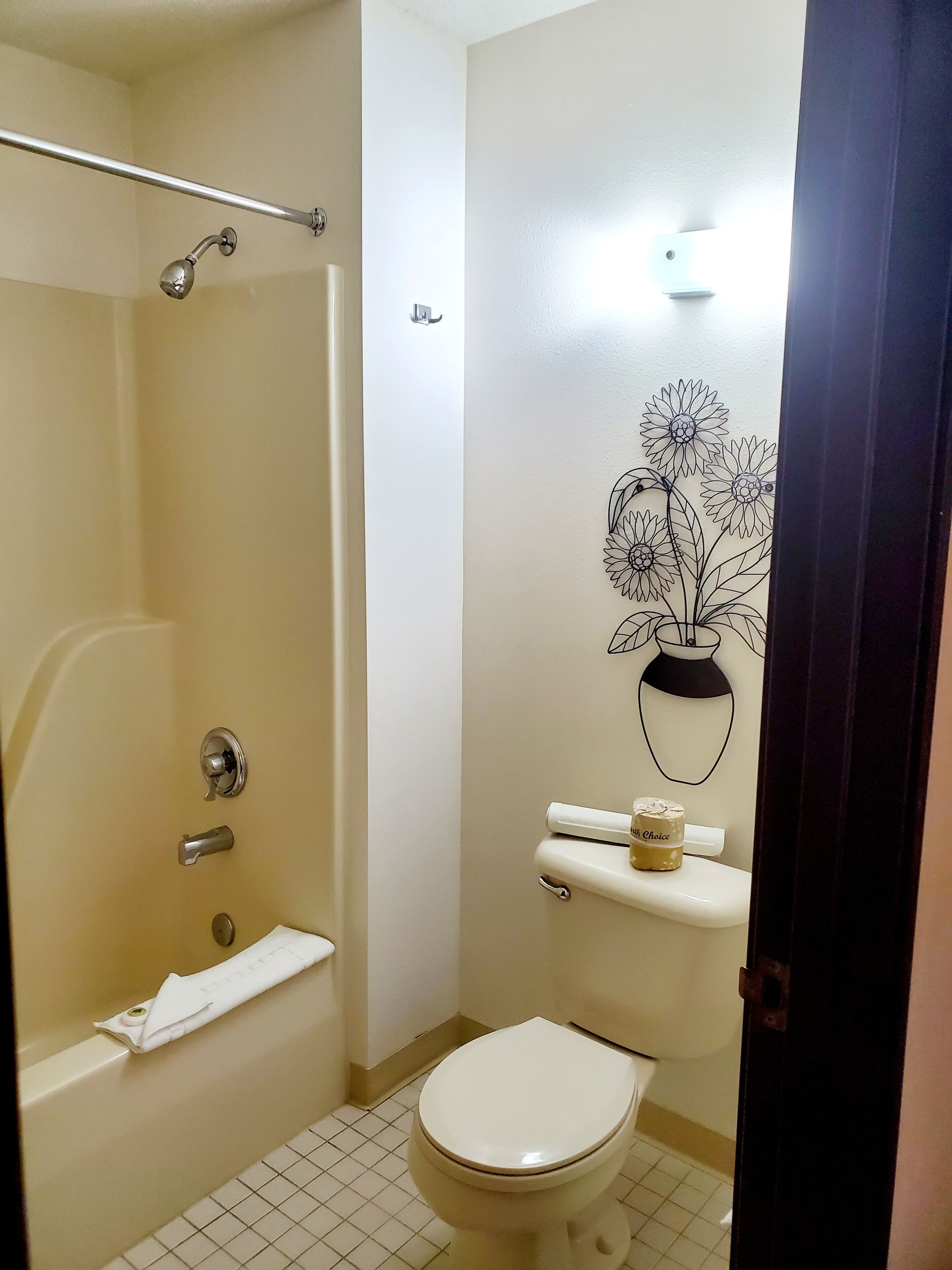 A bathroom with a shower, toilet, and a wall-mounted towel rack.