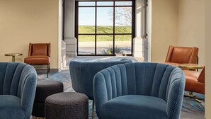 A hotel lobby with a large window, two brown leather chairs, and a blue upholstered sofa. - Days Inn by Wyndham Grand Island I-80 (Grand Island)