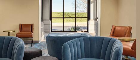 A hotel lobby with a large window, two brown leather chairs, and a blue upholstered sofa.