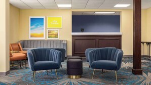 A lobby with two blue armchairs, a sofa, a reception desk, and a patterned carpet. - Days Inn by Wyndham Grand Island I-80 (Grand Island)