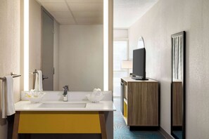 A hotel bathroom with a white sink, a mirror, and a wooden cabinet. - Days Inn by Wyndham Grand Island I-80 (Grand Island)