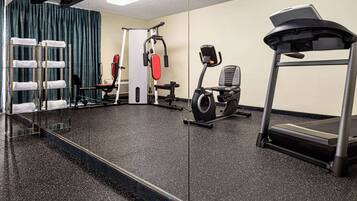 Une salle de sport équipée d’un tapis de course, d’un vélo d’exercice et d’appareils de musculation.