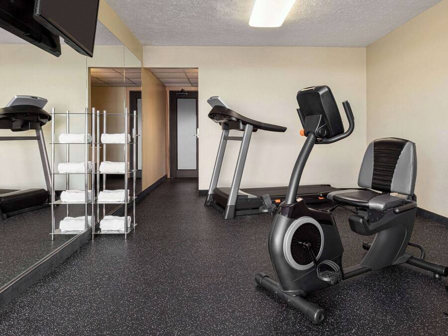 Un gimnasio con equipo de ejercicio, un espejo y un perchero para toallas.