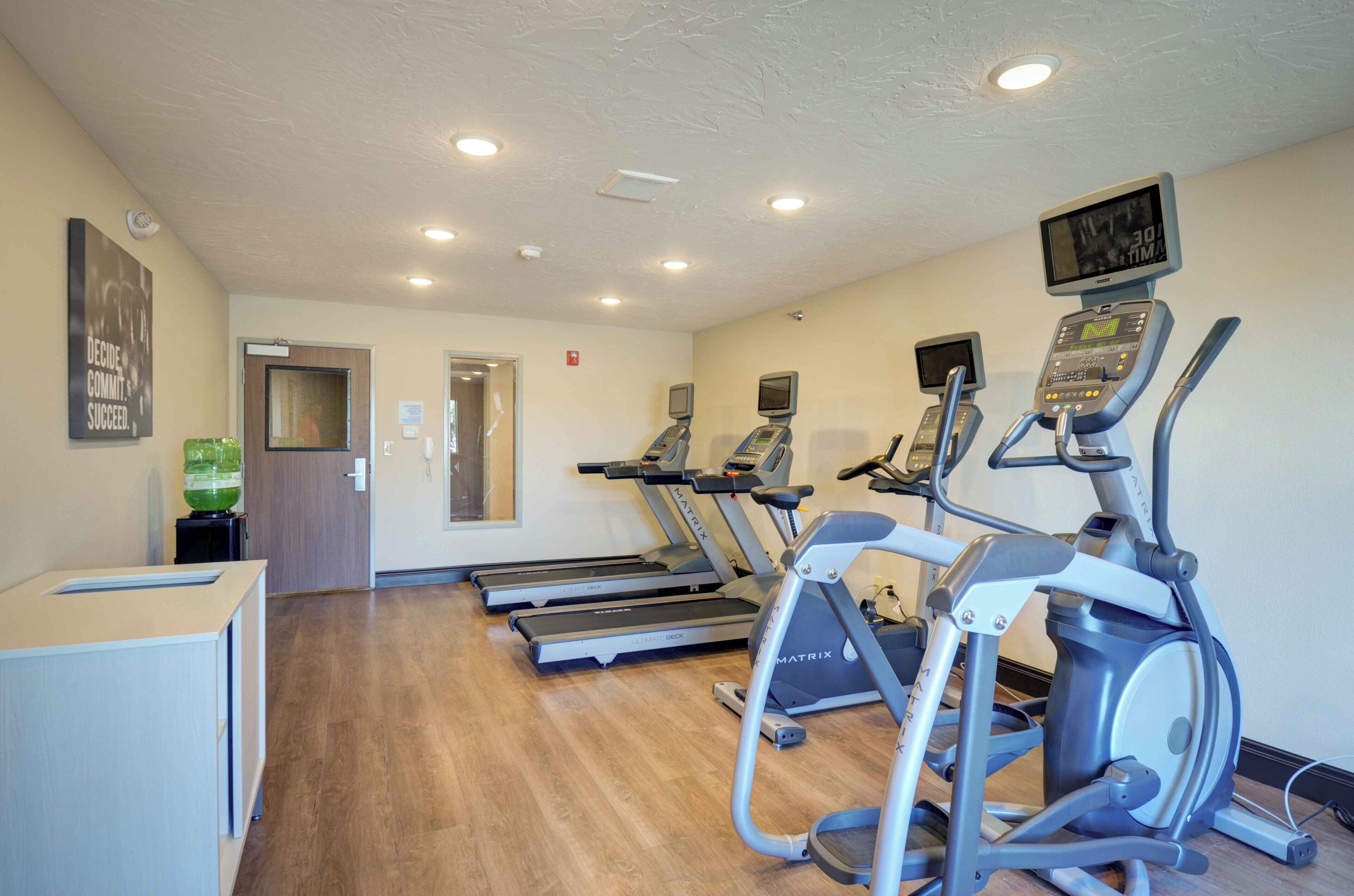 Ein Fitnessstudio mit Laufbändern, Crosstrainern und einer Spiegelwand.