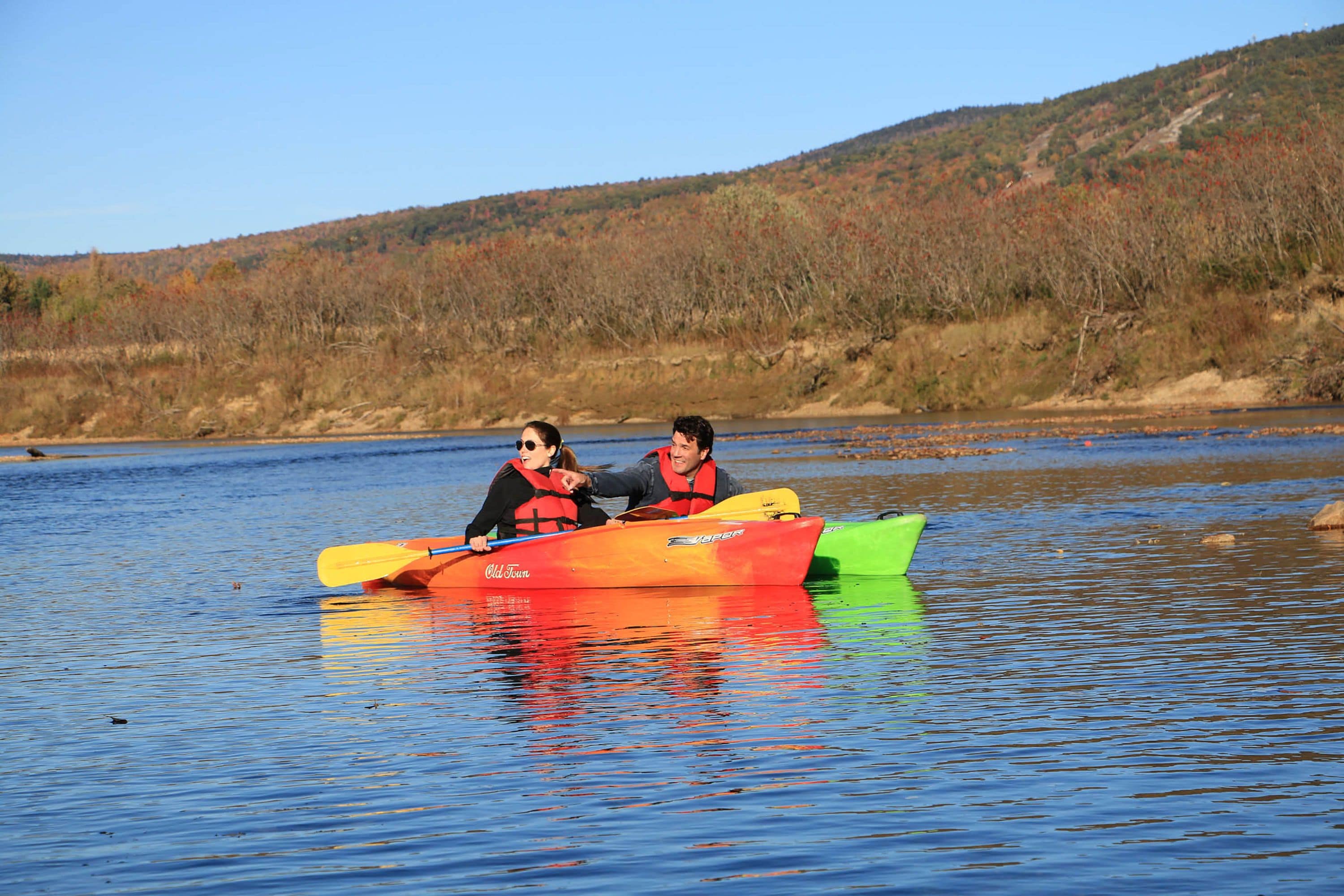 Two people in a colorful canoe on a calm river.