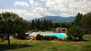 Una piscina con sillones de descanso, un edificio con un letrero y una montaña al fondo.