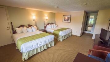 A hotel room with two beds, a TV, and a desk.