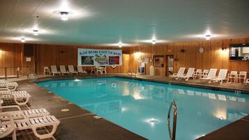 An indoor swimming pool with lounge chairs and a banner advertising a water activity event.