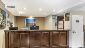 A reception desk with a computer, a printer, and framed certificates on the wall.