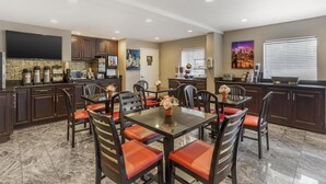 A modern kitchen with dark cabinets, a central island, and a dining area with red cushioned chairs.